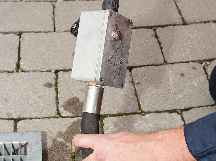 Techniker von PAKO führt eine Dichtheitsprüfung an einem Straßenkanal durch, mit Messeinrichtung am Schacht