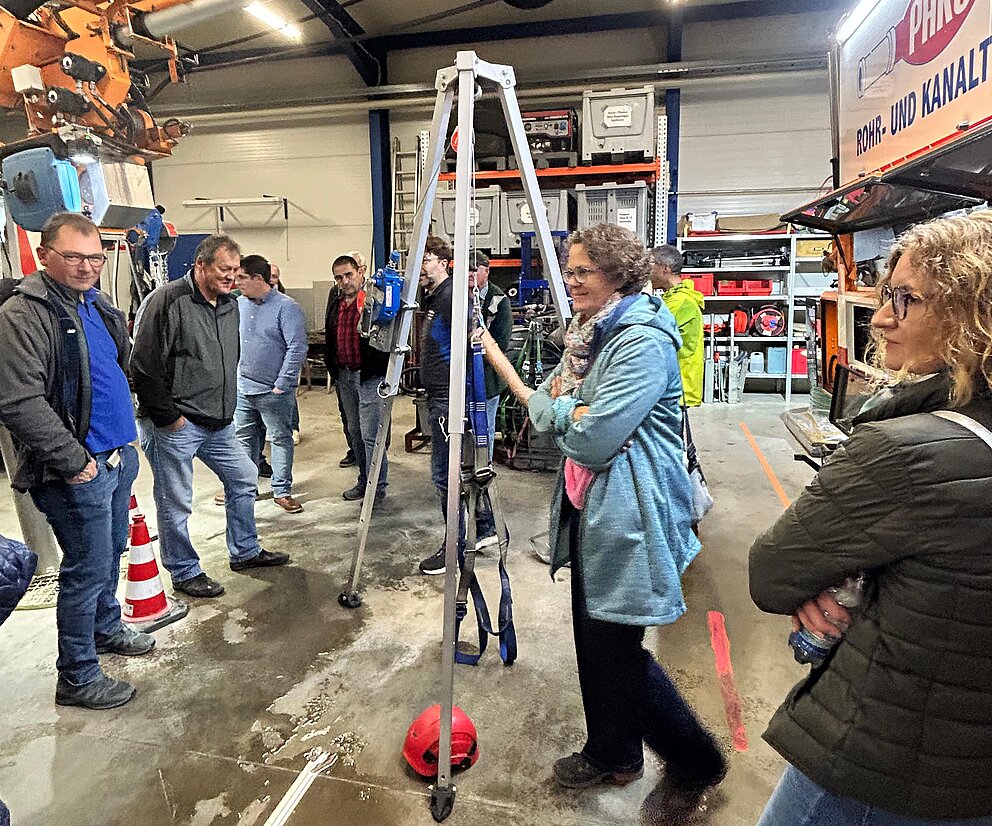Besichtigung Werkhalle mit Krananlage Personengruppe in einer Werkhalle mit großem Kran und Einsatzfahrzeug während einer Führung.