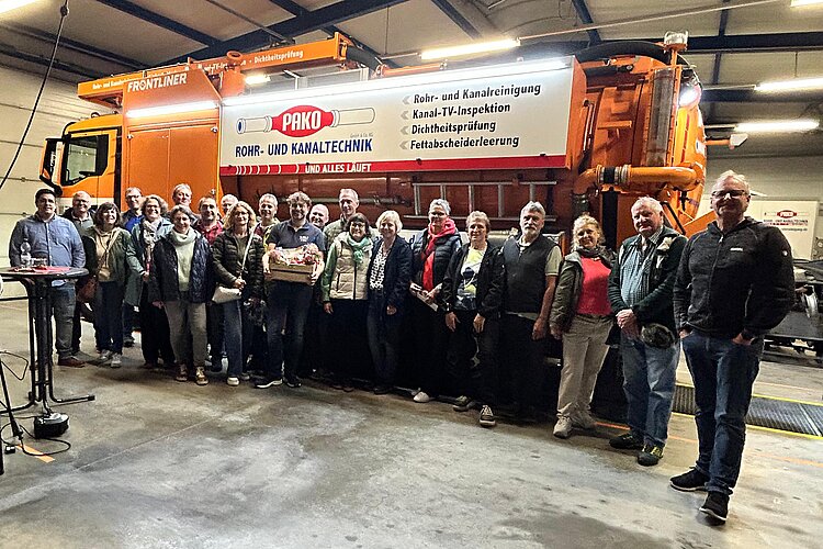 Gruppenbild Gruppenfoto vor einem großen Einsatzfahrzeug in einer Werkhalle während einer Betriebsbesichtigung.