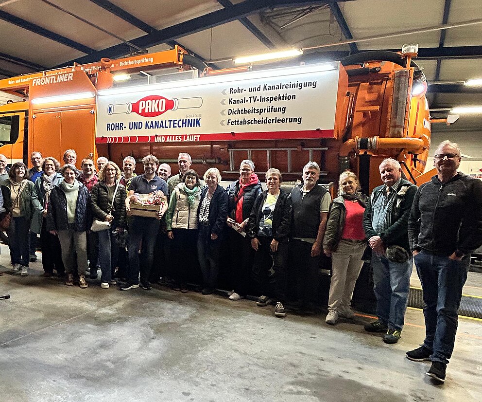 Gruppenbild Gruppenfoto vor einem großen Einsatzfahrzeug in einer Werkhalle während einer Betriebsbesichtigung.