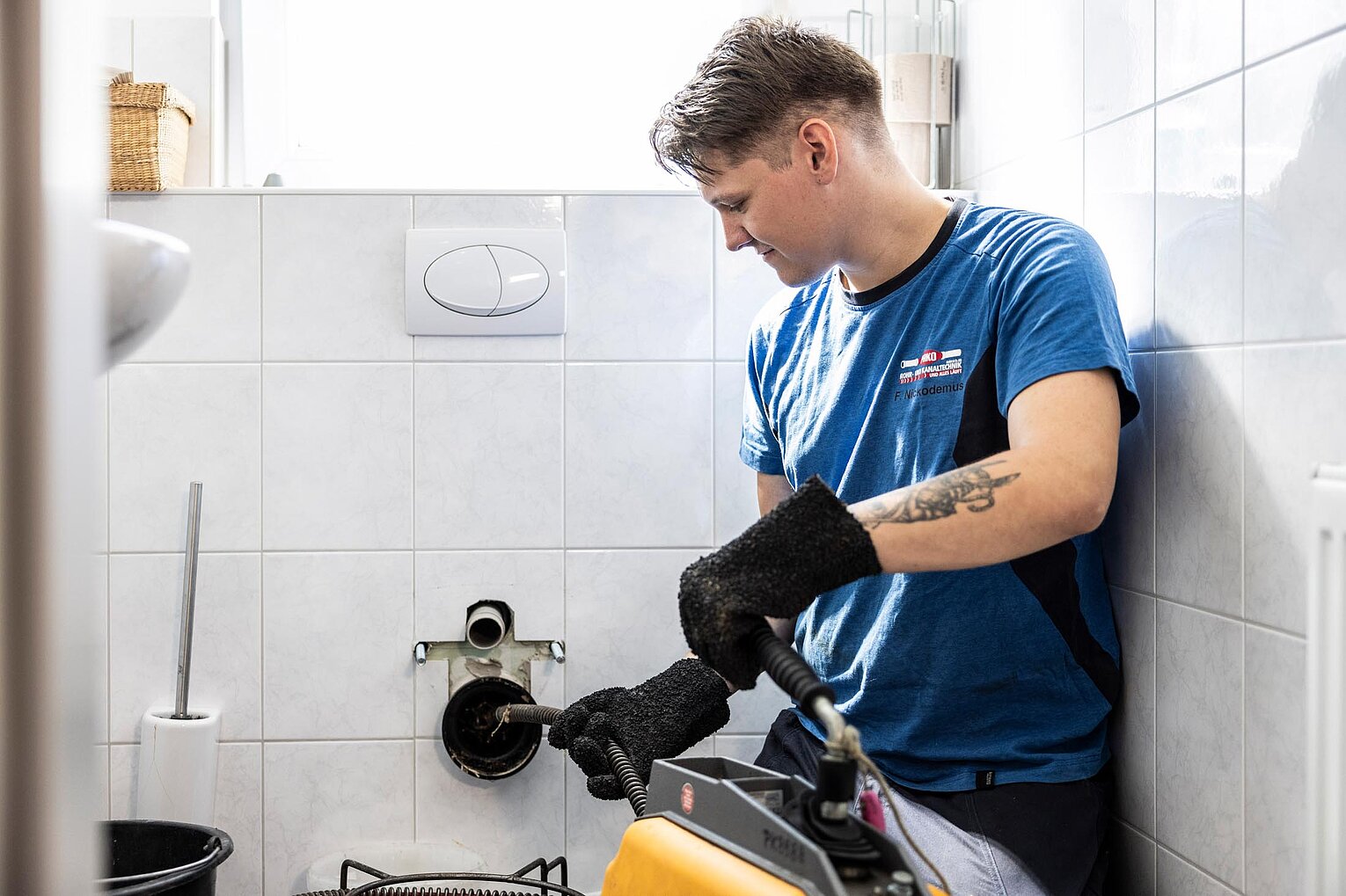 PAKO-Fachkraft reinigt Abfluss in einem Badezimmer mithilfe einer mechanischen Rohrreinigungsspirale