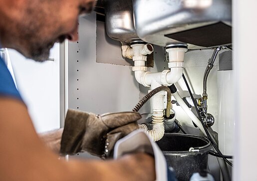 Rohrreinigung in der Küche PAKO-Mitarbeiter bei der Rohrreinigung unter einer Küchenspüle mit professionellem Werkzeug