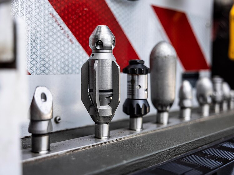 Mehrere Spezialdüsen wie Vorstrahldüse, Rotierdüse, Vibrationsdüse und Rinnendüse für die hydromechanische Kanalreinigung nebeneinander angeordnet.