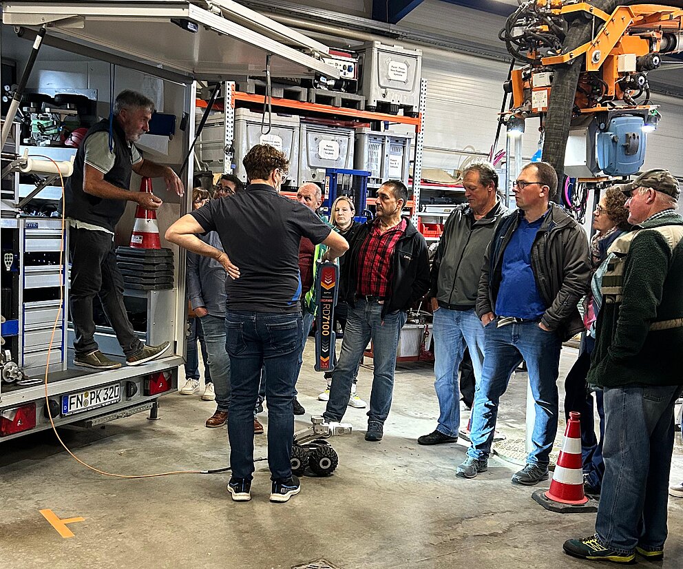 Vortrag über PAKO Gruppe von Personen bei einer Betriebsführung in einer Werkhalle mit Einsatzfahrzeug und technischer Ausrüstung.